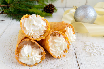 Obraz na płótnie Canvas Crispy honey wafers in the form of cones, filled with air vanilla cream (ice cream) on a white background. Close-up. Treats for the party.