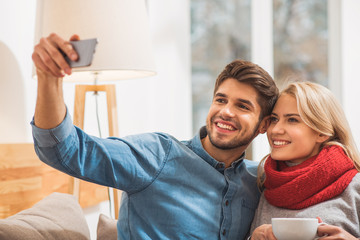Cheerful loving couple photographing themselves on smartphone