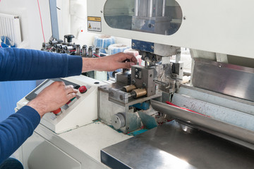 close-up of hands working on industrial machine for cutting cable