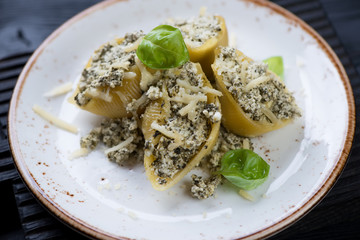 Closeup of a glass plate with baked italian conchiglioni pasta