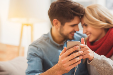 Fototapeta na wymiar Cheerful loving couple entertaining with smartphone