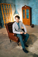 Portrait of a handsome man in gray jacket and blue trousers