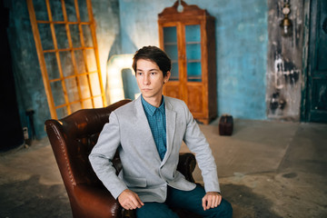 Portrait of a handsome man in gray jacket and blue trousers
