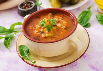 Soup with pickled cucumbers and pearl barley - rassolnik on a light background.