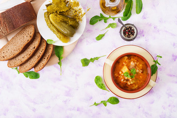 Soup with pickled cucumbers and pearl barley - rassolnik on a light background. Top view. Flat lay