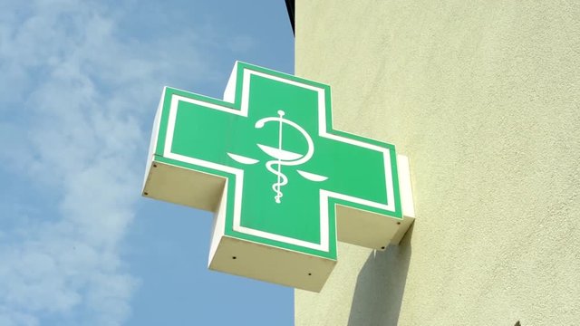 A pharmacy cross symbol on a wall of a building - closeup from below