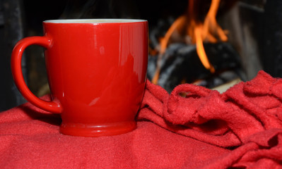 Red cup on red soft blanket with fireplace in background