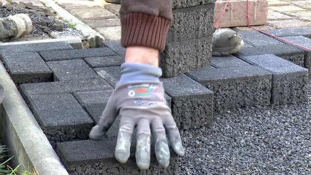 Bauarbeiter verlegt Pflastersteine
(Construction worker laying pavement rocks)