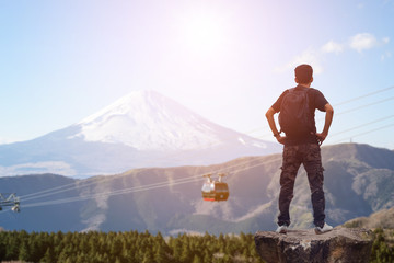 Backpacker standing on the rock and looking at the Mount Fuji in Japan.