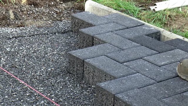 Bauarbeiter verlegt Pflastersteine
(Construction worker laying pavement rocks)