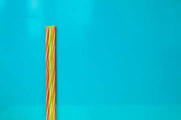 Multicolor drinking straws on blue background. Flat lay with spa