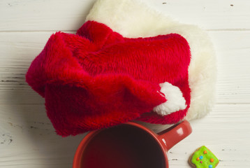 Santa Claus Hat and Cup of Tea on Wooden Background