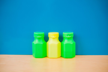 Multicolor bottles on blue background. Green and yellow containe