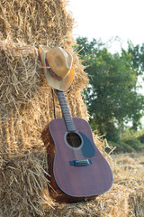 guitar resting on straw Division in the fields, the warm sun of