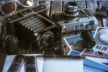 Retro Fotokameras auf einem Tisch / Alte Retro Fotoapparate auf einem Tisch mit Fotografien,...