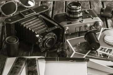 Retro Fotokameras auf einem Tisch / Alte Retro Fotoapparate auf einem Tisch mit Fotografien,...