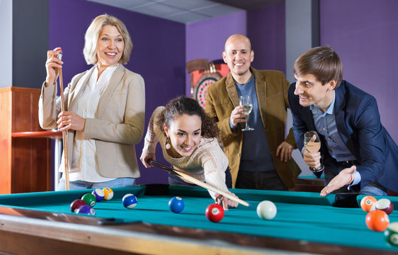 Group of cheerful pretty positive friends playing billiards