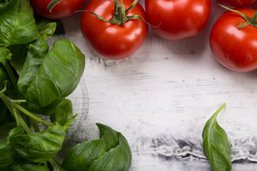 Fresh tomatoes and basil leaves on white background