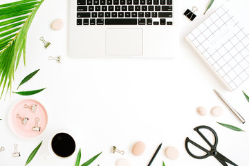 Flat lay, top view frame of office table desk. Workspace with notebook, laptop, palm branch, coffee cup, scissors and clips on white background.