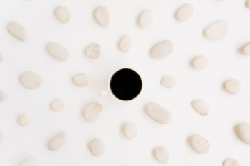 Black coffee cup with neutral pattern of beige stones. Flat lay, top view