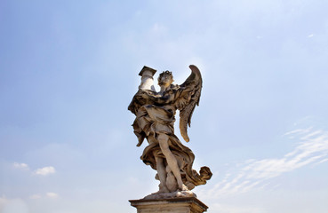 View of winged man statue with clear blue sky background at St. Angelo bridge in Rome. It was built in 134 A.D., with travertine marble fascias & spanning the River Tiber.