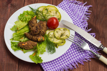 Meat dish called fingers with greens. Wooden table. Close-up