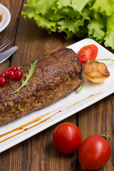 Meatloaf stuffed with mushrooms  sauce and berries. Wooden rustic background. Close-up
