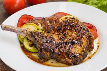 Pork steak on the bone grilled with vegetables. Wooden background. Top view. Close-up