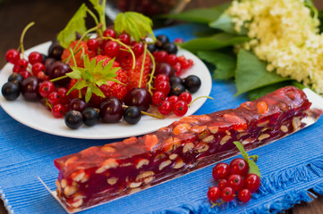 Churchkhela Georgian national delicacy, with different sweets and berries on a background of flowers. Wooden table. Close-up