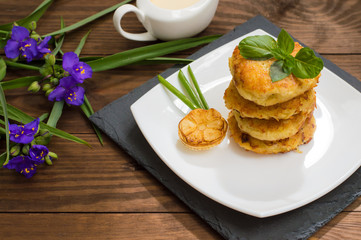 Potato pancakes with sour cream sauce on the background color. Wooden table. Close-up