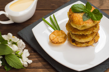 Potato pancakes with sour cream sauce on the background color. Wooden table. Close-up
