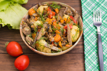 Braised liver with onions, carrots, potatoes and spices on stone plate. Wooden background. Top view. Close-up