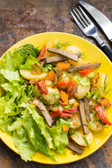 Salad from liver, carrots, potatoes, peppers and lettuce. Wooden table Top view. Close-up