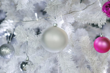 Fototapeta na wymiar Christmas balls white and pink hanging on white Christmas tree