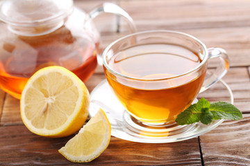 Cup of tea with mint and lemon on brown wooden table