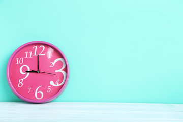Pink round clock on a green background