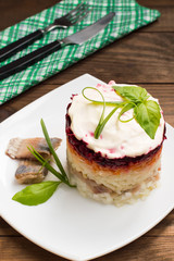 Shuba salad. Cooked beets, carrots, potatoes, onions, herring and mayonnaise. The classic Russian cuisine. Restaurant supply. Wooden table. Close-up. Top view