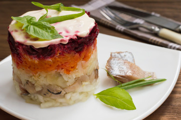Shuba salad. Cooked beets, carrots, potatoes, onions, herring and mayonnaise. The classic Russian cuisine. Restaurant supply. Wooden table. Close-up. Top view
