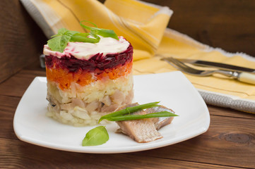 Shuba salad. Cooked beets, carrots, potatoes, onions, herring and mayonnaise. The classic Russian cuisine. Restaurant supply. Wooden table. Close-up. Top view