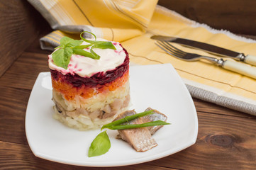 Shuba salad. Cooked beets, carrots, potatoes, onions, herring and mayonnaise. The classic Russian cuisine. Restaurant supply. Wooden table. Close-up. Top view