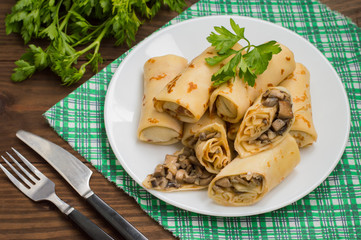 Pancakes stuffed with mushrooms and sour cream on a rustic wooden table. Top view. Close-up