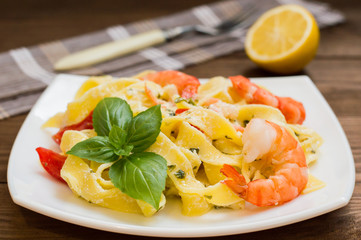 Fettuccine pasta in cream sauce with king prawns on a plate  the wooden table. Horizontal view from above. Top . Close-up