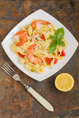 Fettuccine pasta in cream sauce with king prawns on a plate  the wooden table. Top view