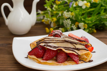 Pancakes with strawberries, topped  chocolate. Wooden table. Top view