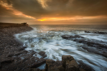 Fototapeta premium Sunrise and a choppy sea at Porthcawl lighthouse in South Glamorgan, South Wales