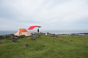 Orange camping tent on a shore 