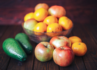 Blurred image of fresh fruit on a table: apples, mandarines and avocado. 