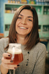 Ragazza sorridente con la birra in un pub