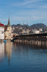 Fototapeta na wymiar Svizzera, 08/12/2016: lo skyline della città medievale di Lucerna con vista del famoso Ponte della Cappella, il ponte pedonale coperto in legno che attraversa il fiume Reuss