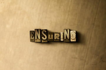 ENSURING - close-up of grungy vintage typeset word on metal backdrop. Royalty free stock - 3D rendered stock image.  Can be used for online banner ads and direct mail.